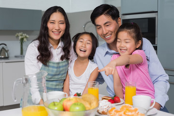 Cheerful family of four enjoying healthy breakfast in kitchen