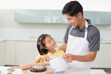Man with his daughter preparing dough in kitchen