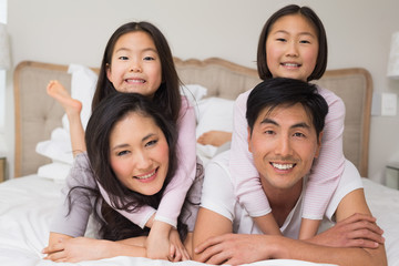 Loving family of four lying in bed at home