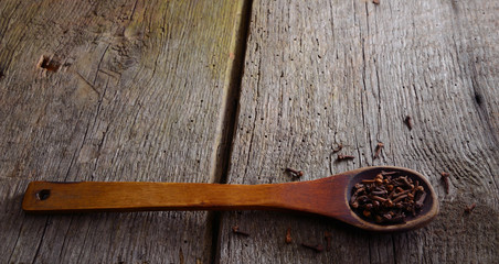 Wooden spoon with a clove. Background with old natural boards.