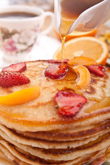 stack of pancakes with syrup and fruit