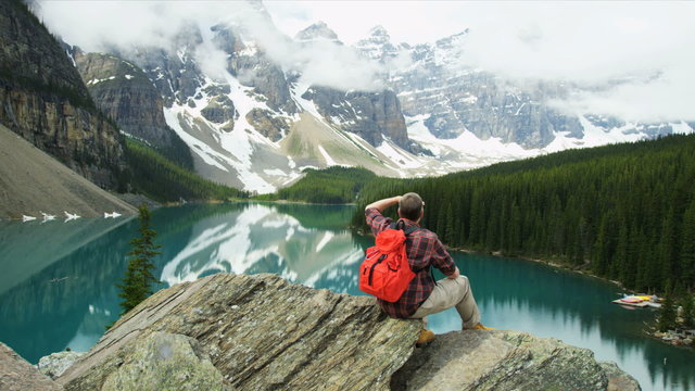 Male hiker viewing turquoise Lake Moraine, Alberta, Canada