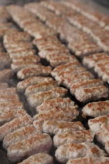 Delicious Balkan cevapi, meat rolls on the smoking BBQ