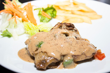 Beef steak with black pepper sauce on a white plate