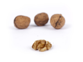 Peeled walnut with closed nutshells behind it