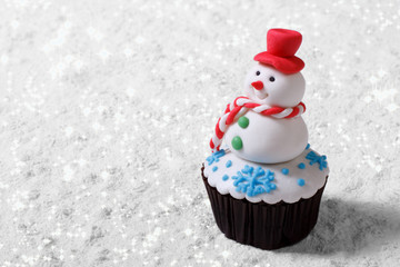 Cupcake Christmas snowman on white snow. horizontal