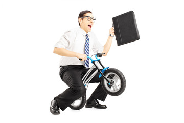 Fototapeta na wymiar Excited young businessman with leather suitcase riding a bike