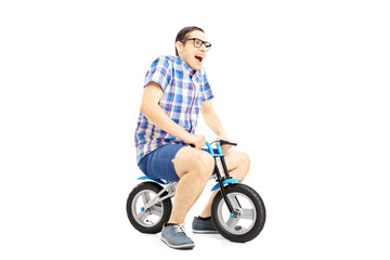 Fototapeta na wymiar Excited young male riding a small bicycle