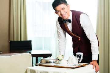 Asian Chinese room service waiter serving food in hotel