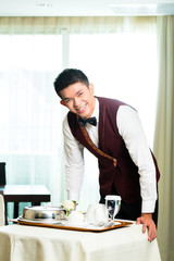 Asian Chinese room service waiter serving food in hotel