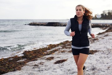 Young attractive woman jogging on a sandy beach