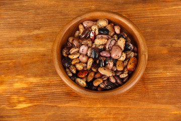 Wooden bowl with beans on wooden background