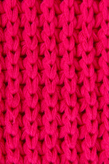 Warm knitted scarf pink background close-up