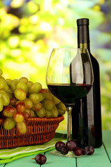 Ripe grapes in wicker basket, bottle and glass of wine,