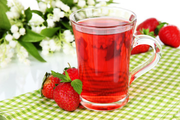 Delicious strawberry tea on table on white background