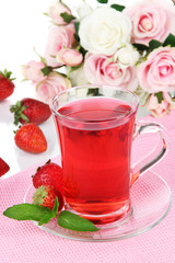 Delicious strawberry tea on table on white background