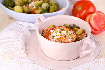 Stuffed tomatoes in pan and bowl on wooden table close-up