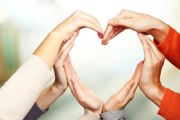 Human hands in heart shape on bright background