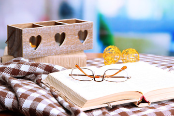 Composition with old book, eye glasses, candles, and plaid