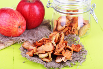 Dried apples in glass jar, on color wooden background