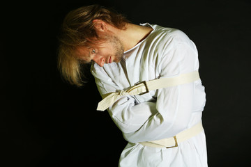 Mentally ill man in strait-jacket on black background