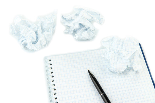 Crumpled paper balls with notebook and pen isolated on white