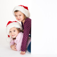 Lachende Kinder mit Nikolausmützen hinter Werbeschild