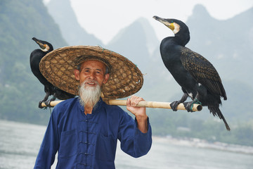 Chinesischer alter Mensch mit Kormoran zum Angeln
