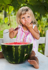 blonde litle girl eats a slice of watermelon