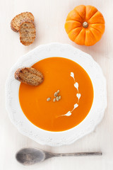 Pumpkin soup with croutons and pumpkin seeds in a white plate