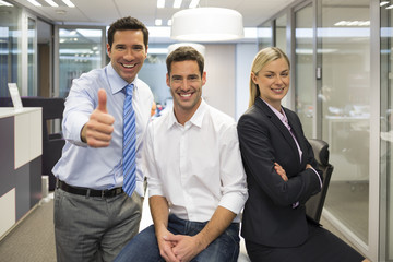 Portrait of joyful business team, man showing thumb up, office