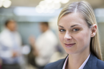 Businesswoman posing while colleagues talking together in office