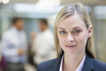 Businesswoman posing while colleagues talking together in office