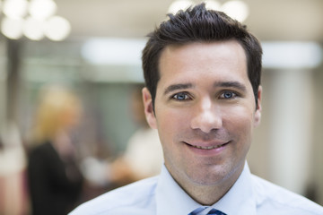 Smiling Businessman posing while colleagues talking Background