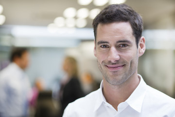 Smiling Businessman posing while colleagues talking together