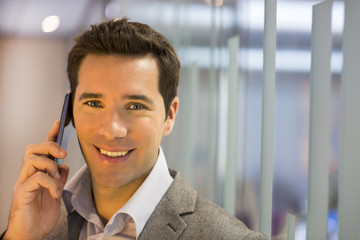 Smiling businessman talking on cell phone, looking camera
