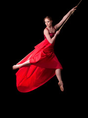 oung woman gymnast on rope on black background