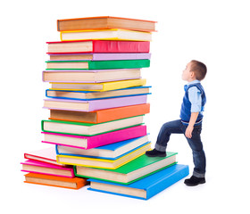 Little boy looking up to stacked big books