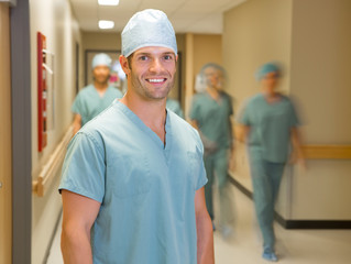 Happy Doctor With Team At Hospital Corridor