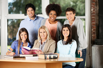 Students And Teacher With Books Smiling In Classroom