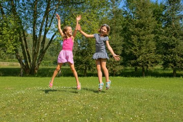 Naklejka na ściany i meble Children, girls laughing while having fun in a meadow