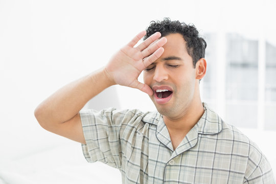 Close-up of a young man yawning in bed