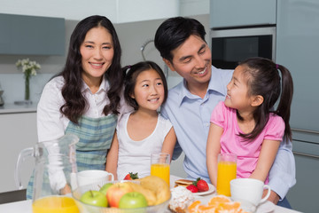 Cheerful family of four enjoying healthy breakfast in kitchen