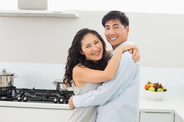 Young man embracing woman in kitchen