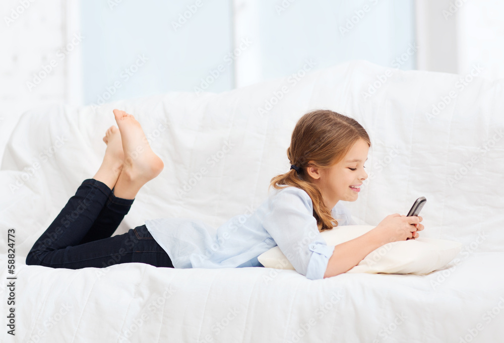 Wall mural smiling girl with smartphone at home