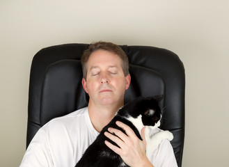 Mature Man and his cat relaxing in massage chair