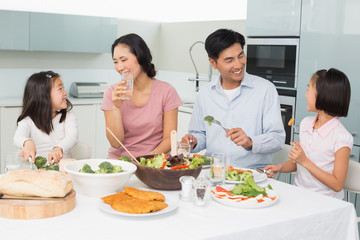 Young family of four enjoying healthy meal in kitchen