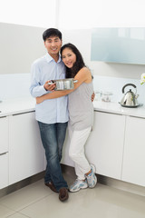 Portrait of a young woman embracing man in kitchen