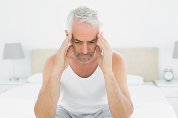 Mature man suffering from headache in bed
