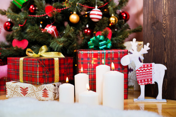 candle on the background of the Christmas tree with gifts